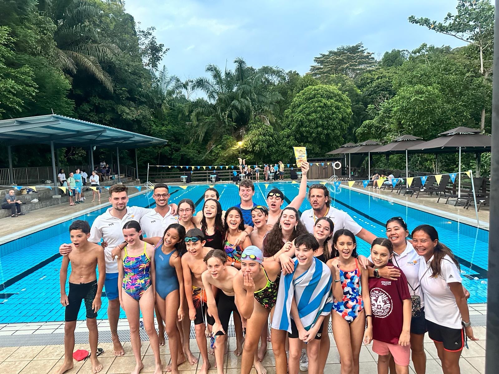 Coach Tiago Escada with a youth swim team at an outdoor pool